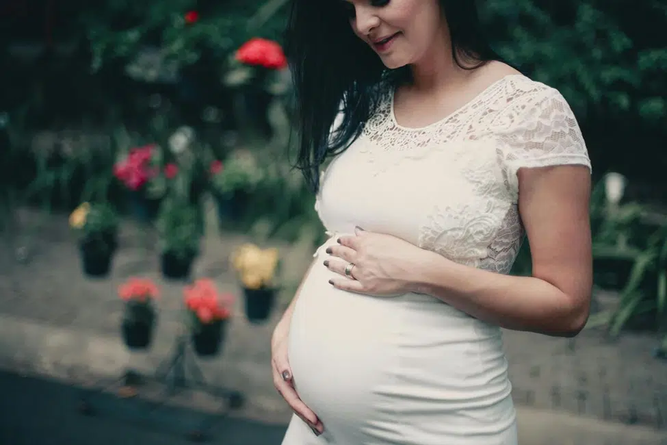 Pregnant woman holding belly with concern, symbolizing leaking amniotic fluid during late pregnancy