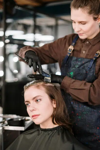 Pregnant woman looking at her dyed hair in mirror at home salon