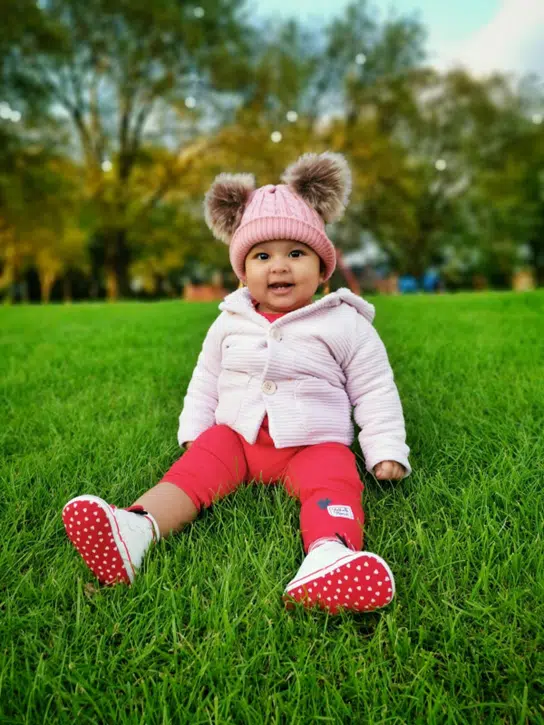 Newborn baby girl dressed in cozy fall clothes with knit hat, cardigan, and leggings on a soft autumn blanket