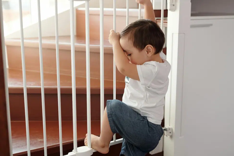 "White baby safety gate securely installed at the top of a staircase to prevent toddler falls"