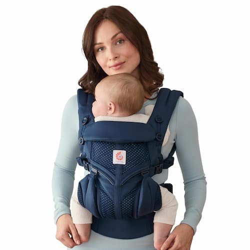 A mother wearing an Ergobaby Omni 360 Cool Air Mesh carrier in midnight blue, demonstrating safe infant M-position seat placement optimized for plus-sized parental ergonomic support.