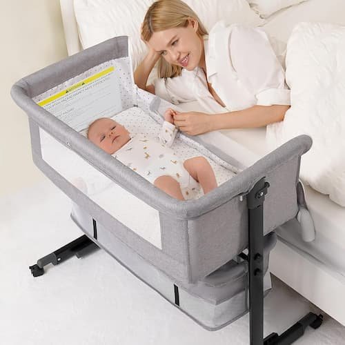 A mother sleeping peacefully next to her newborn in a 3-in-1 grey baby bassinet with breathable mesh, featuring height-adjustable settings for safe bedside sleeping.