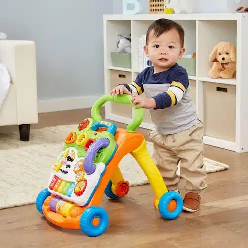 A toddler using the VTech Sit-to-Stand Learning Walker with its interactive toy panel active.